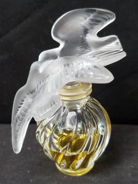 A Glass Bird On Top Of A Bottle Filled With Oil