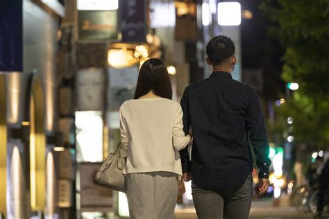 夜の繁華街で手を繋いで歩く男女の後ろ姿 交際クラブ 東京・六本木・西麻布 Rn246