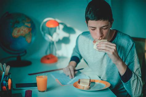 Teenage Boy Eating Breakfast In His Room Stock Photo Download Image