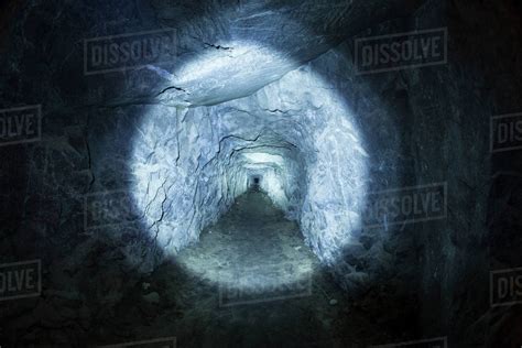 Photograph Of Tunnel In Cave Illuminated By Flashlight