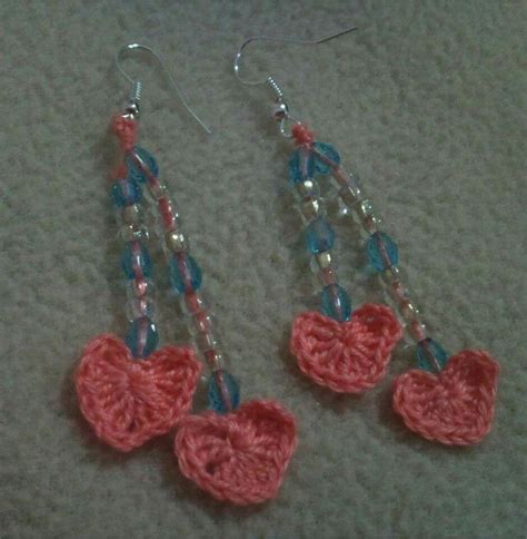 Two Crocheted Hearts Are Hanging From Earrings