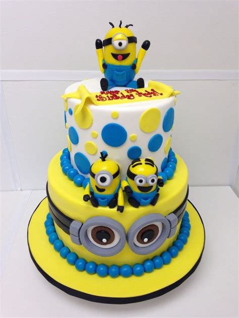 A Yellow And Blue Cake With Two Minion Characters On Its Top Tier