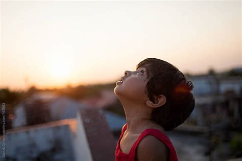 Little Girl Looking Up To The Sky At Sunset By Saptak Ganguly Stocksy