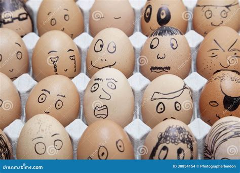 Funny Faces On Painted On Brown Eggs Arranged In Carton Stock Photo