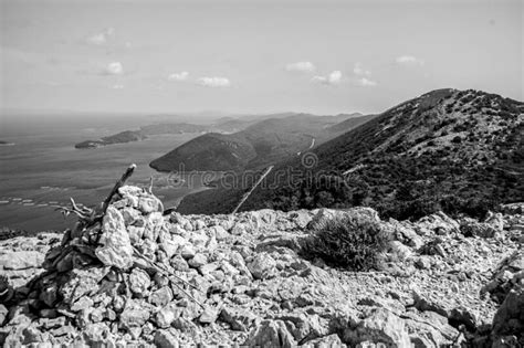 Grayscale Shot Of A Rocky Hill Surrounded By A Lake Stock Image Image