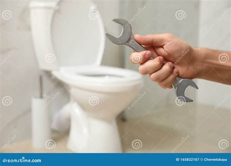 Professional Plumber Holding Wrench Near Toilet Bowl In Bathroom Stock