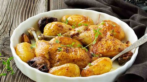 A White Bowl Filled With Potatoes And Mushrooms On Top Of A Wooden Table Next To A Fork