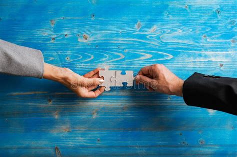 Hands Of Businessman And Businesswoman Matching Two Blank Puzzle Pieces