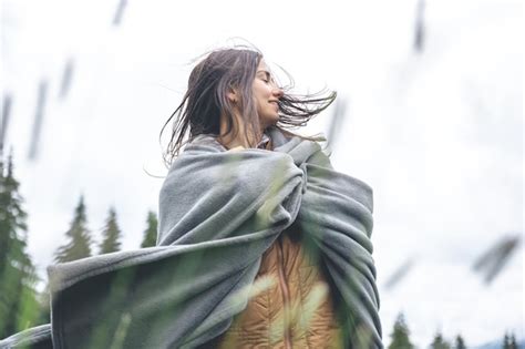 Una mujer joven envuelta en una manta en las montañas Foto Premium