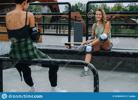 Two Adult Skater Girls Sitting One In Front Of The Other At Skatepark Stock Image Image Of