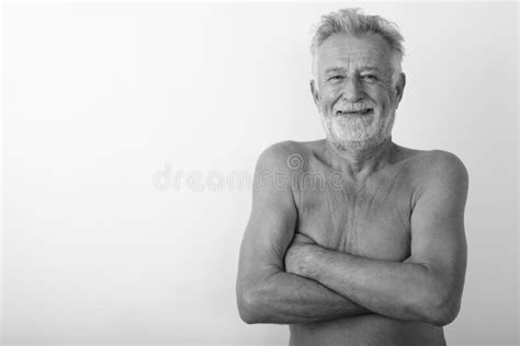 Studio Shot Of Happy Senior Bearded Man Smiling Shirtless With Arms Crossed Against White