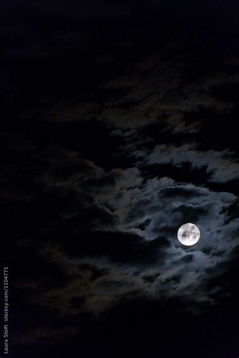 The Full Moon Is Shining Brightly In The Night Sky With Clouds And Dark