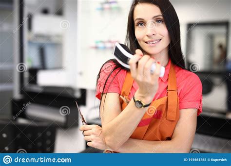 beautiful woman hold scissors in one hand in other hand hold hair clipper in hairdresser stock