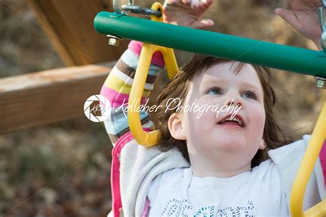 Young Girl Having Fun Outside At Park On A Playground Swing Set