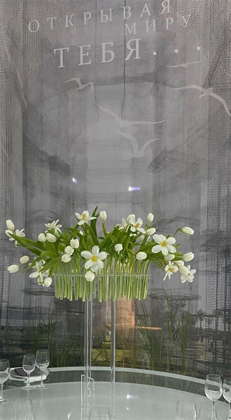 A Vase Filled With White Flowers Sitting On Top Of A Table Next To Wine