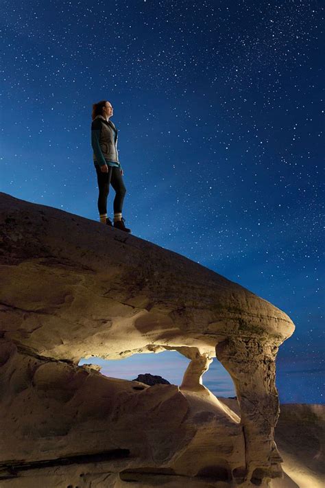 Woman Standing On Rock Arch At Night Looking At Stars Valley Of Fire