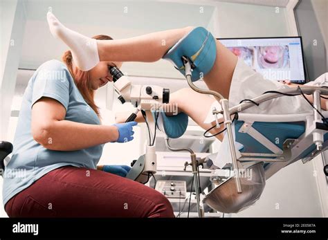 Side View Of Gynecologist Using Colposcope While Examining Woman In