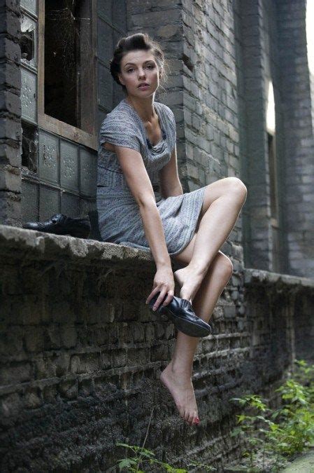 a woman sitting on the ledge of an old brick building with her feet up in the air