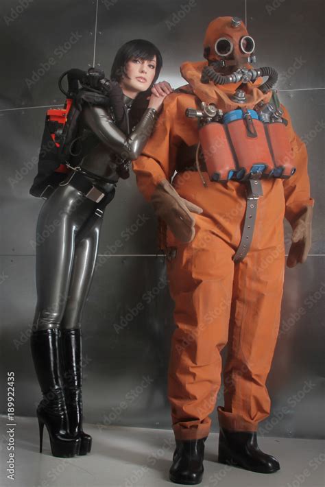 man dressed in historical diving retro costume posing with woman in a latex rubber fetish