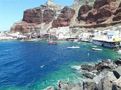 The Picturesque Ammoudi Bay And Port Surrounded By Steep Cliffs Near