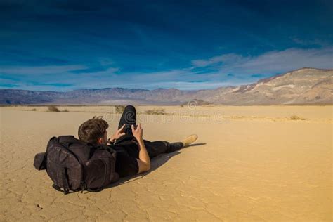 Handsome Athletic Young Man Looking At His Photos Lying In The Desert