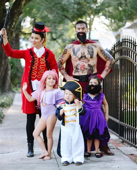 A Group Of People In Costumes Standing On A Sidewalk Next To A Fence And Trees