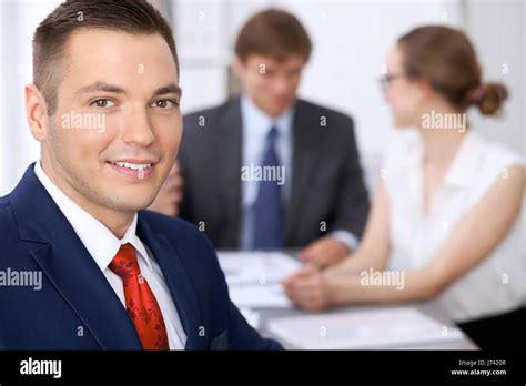 Portrait Of Cheerful Smiling Business Man Against A Group Of Business