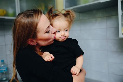 Madre Besando A Su Hija Y La Niña Con La Lengua Fuera