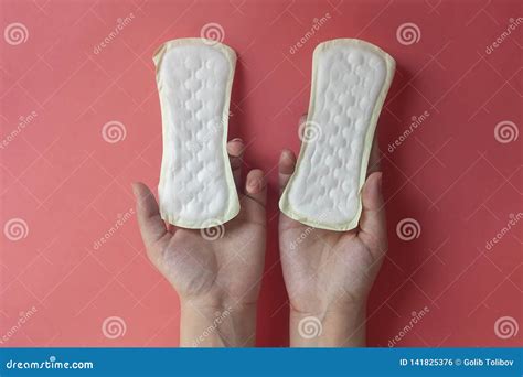 woman`s hands holding two feminine hygiene pads hands of female hold menstrual pads or sanitary