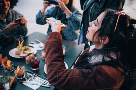 Friends Taking Photos Of Their Food And Drinks At Outdoor Cafe Milan