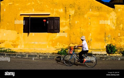 A Vietnamese Woman Rides A Bike Along A Street In The Old Town Of Hoi