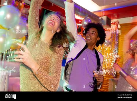 Happy Diverse Couple Dancing And Drinking Champagne At A Nightclub