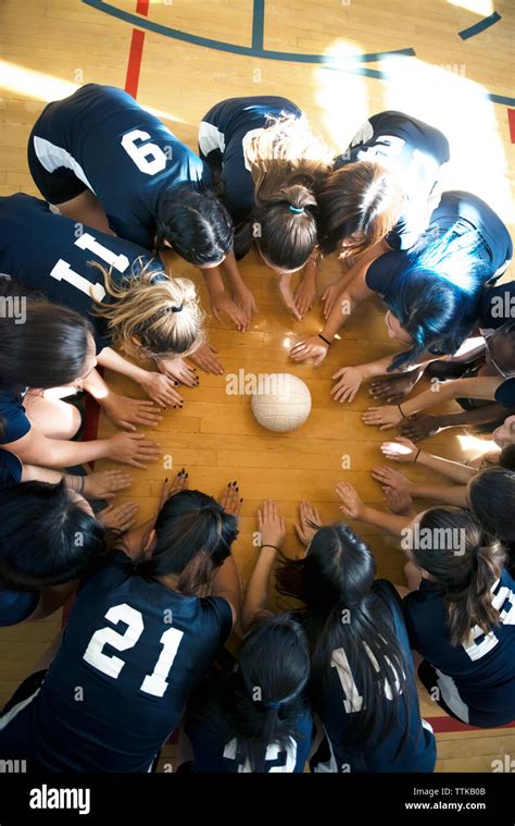 High Angle View Of Girls Volleyball Team Huddling On Floor Stock Photo
