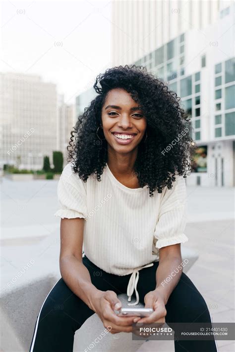 Portrait of smiling African-American woman sitting on city street with