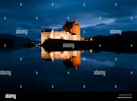 Eilean Donan Castle With Reflection In Loch Water Lit Up At Night