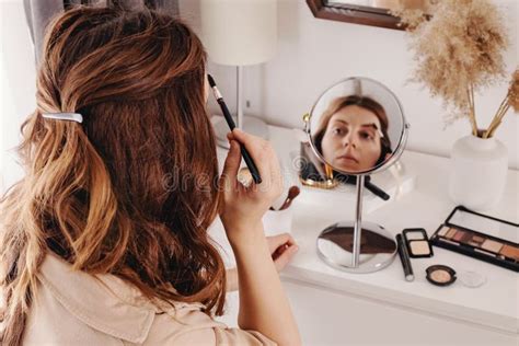 Joven Mujer Que Se Maquilla En La Cara Mirando El Espejo Redondo Foto