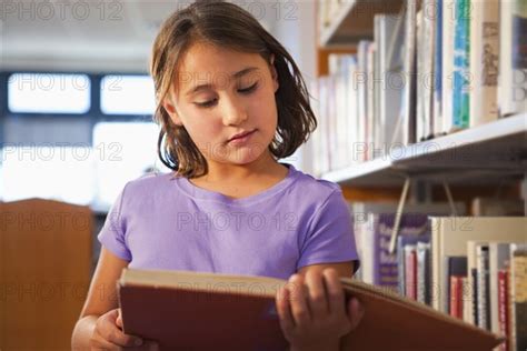 Mixed Race Girl Reading Book In Library Photo12 Tetra Images Marc