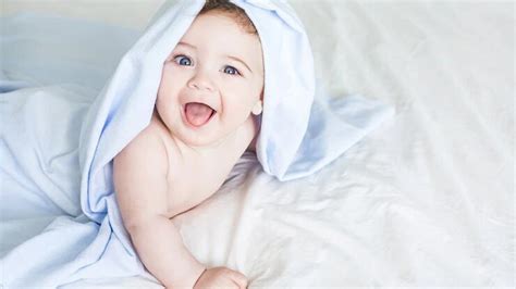 Laughing Newborn Boy Toddler Is Lying Down On White Bed Covering With