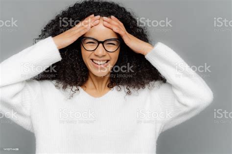 Indoor Shot Of Glad Optimistic Dark Skinned Lady Touches Forehead Has