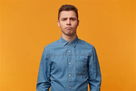 Free Photo A Young Sad Guy Stands With A Gloomy Facial Expression