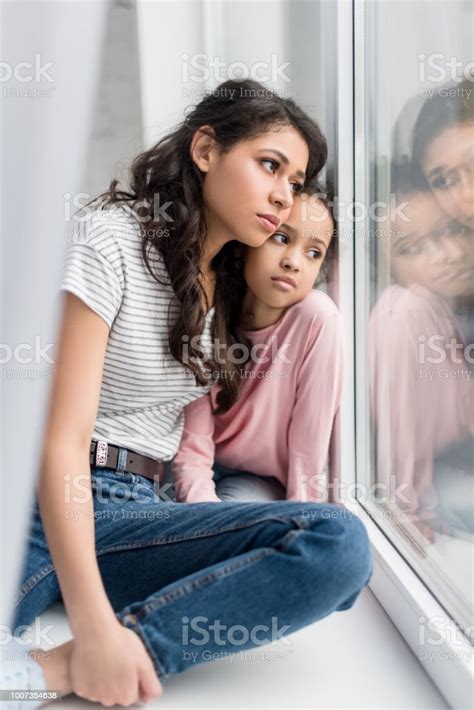 Sad Mother And Daughter Looking Through Window Stock Photo Download