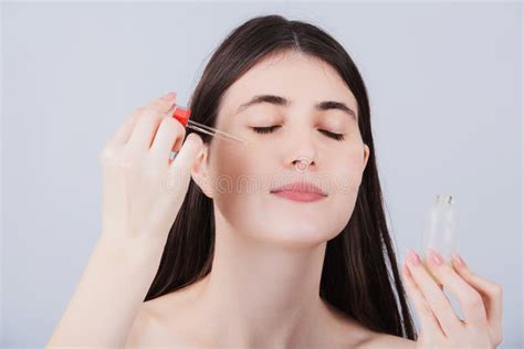Young Woman Applying Cosmetic Facial Oil On Face With Pipettenatural