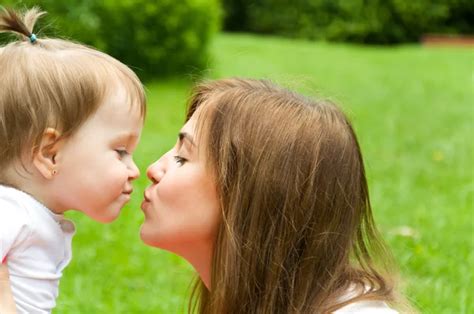 Madre Besando A Su Hijo En La Mejilla Durante El Verano Fotografía De