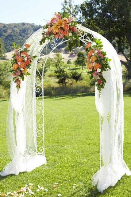 A Golf Course Wedding Arch With Tulle Draping And Orange