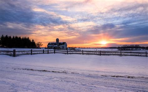 Winter Sunset Over A Fence And Snow Covered Farm Field In Rural Stock
