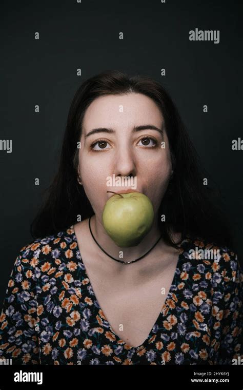 Girl Close Up Biting Apple On Dark Bacground Like Magriite Painting
