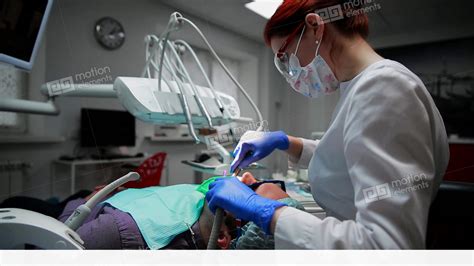 A Woman Holds A Dentist Drilling Patients Tooth And The Fence The