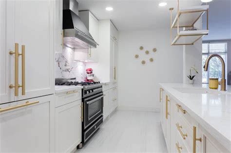 A Kitchen With White Shaker Cabinets And Gold Brass Hardware