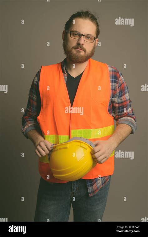 Young Bearded Man Construction Worker Against Gray Background Stock