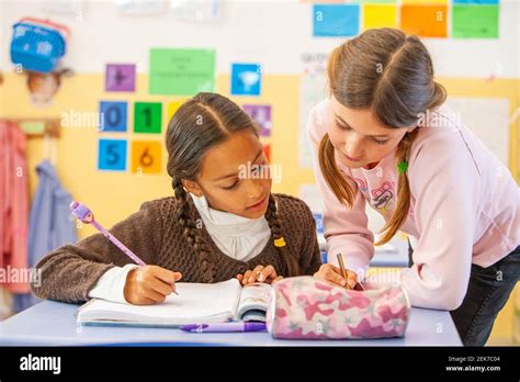 Young Girls Helping Each Other In A School Classroom Stock Photo Alamy